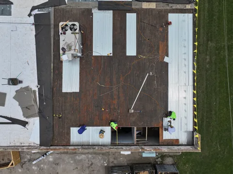 Crew installing a white TPO membrane on a commercial roof in Bedford, Texas